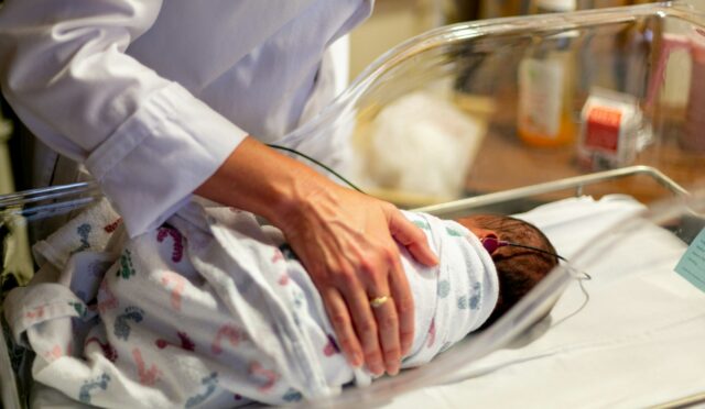 person in white scrub suit holding clear glass container