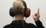 a woman wearing headphones pointing to the side