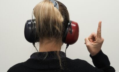 a woman wearing headphones pointing to the side