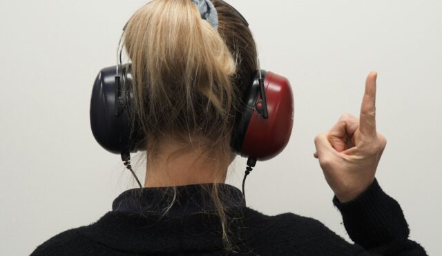 a woman wearing headphones pointing to the side